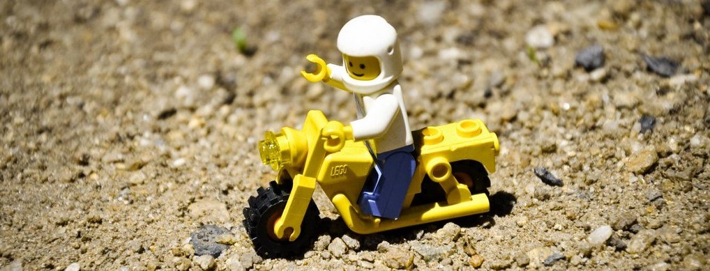 A picture of a LEGO on a yellow bike, and he's wearing a helmet!