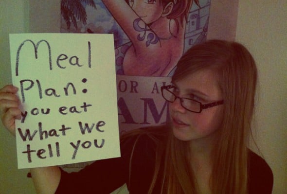 College student holds up meal plan sign: eat what we tell you