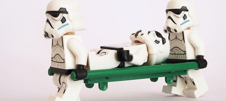 Two Stormtroopers carrying out a third, likely after leg day and DOMS.