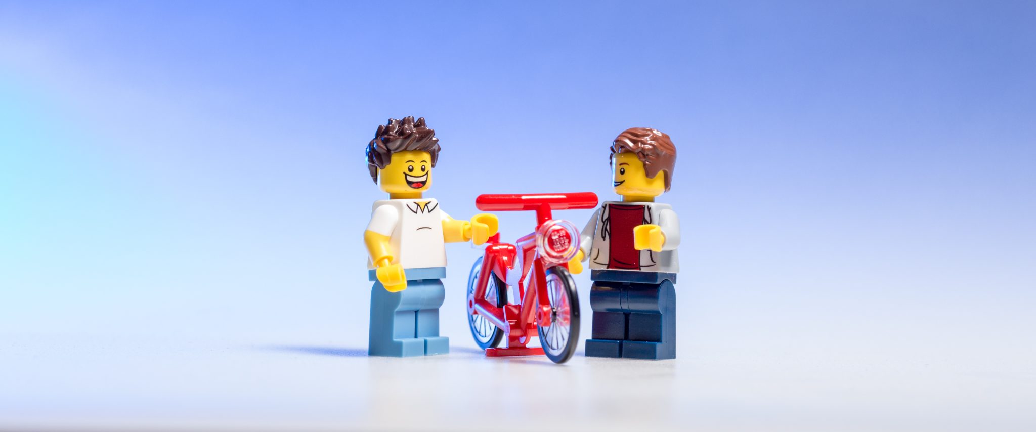 Two LEGOs discussing a bicycle. 