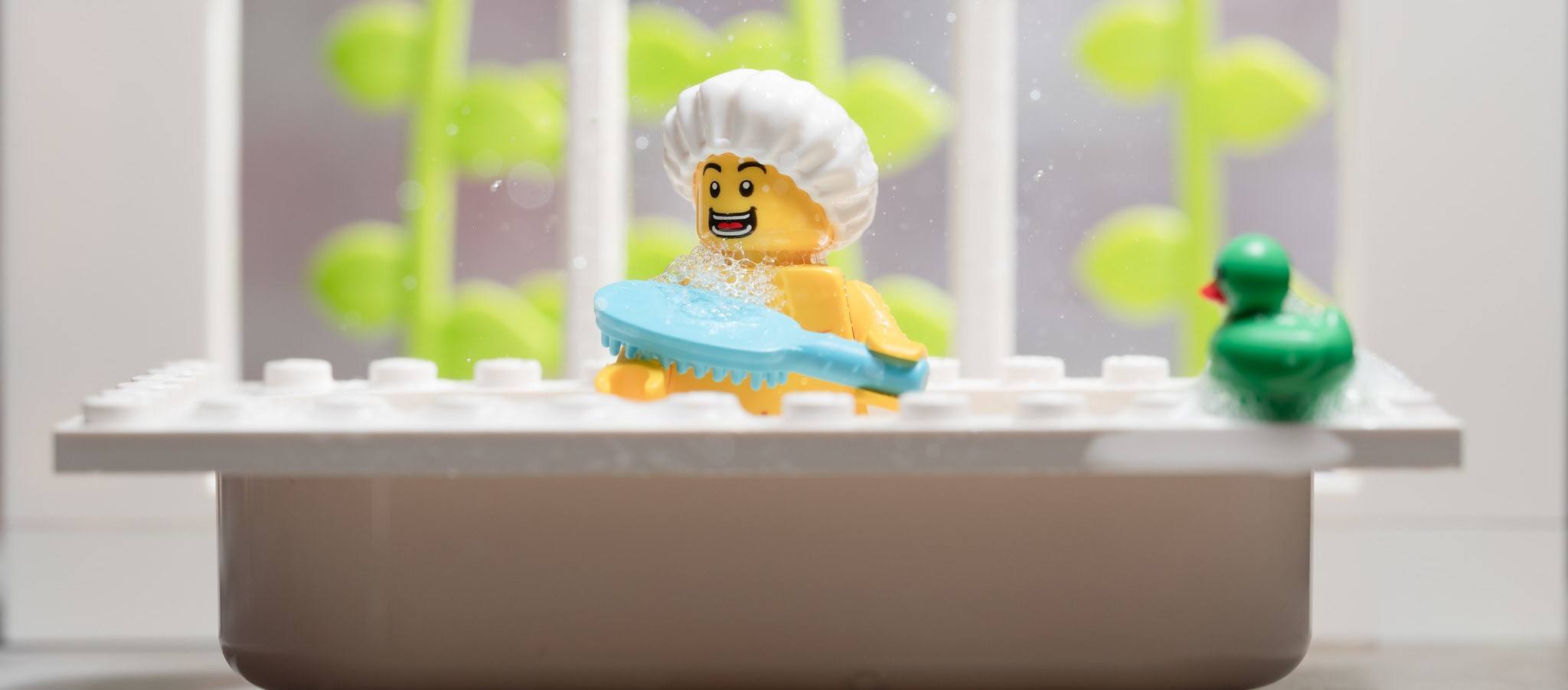 A LEGO in the bathtub, bathing with his duck.