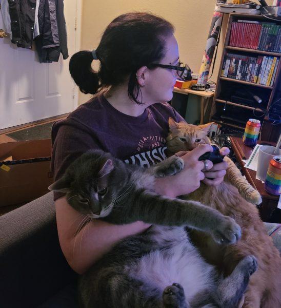 Ranada gaming with one of her cats in each arm